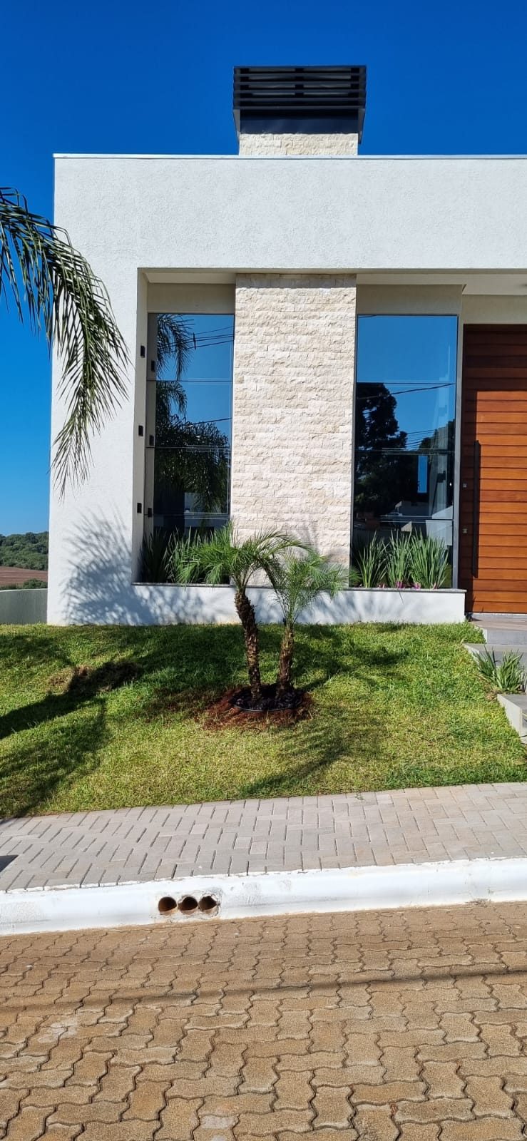 Fachada branca com uma faixa vertical de rock face de travertino entre dois panos de vidro