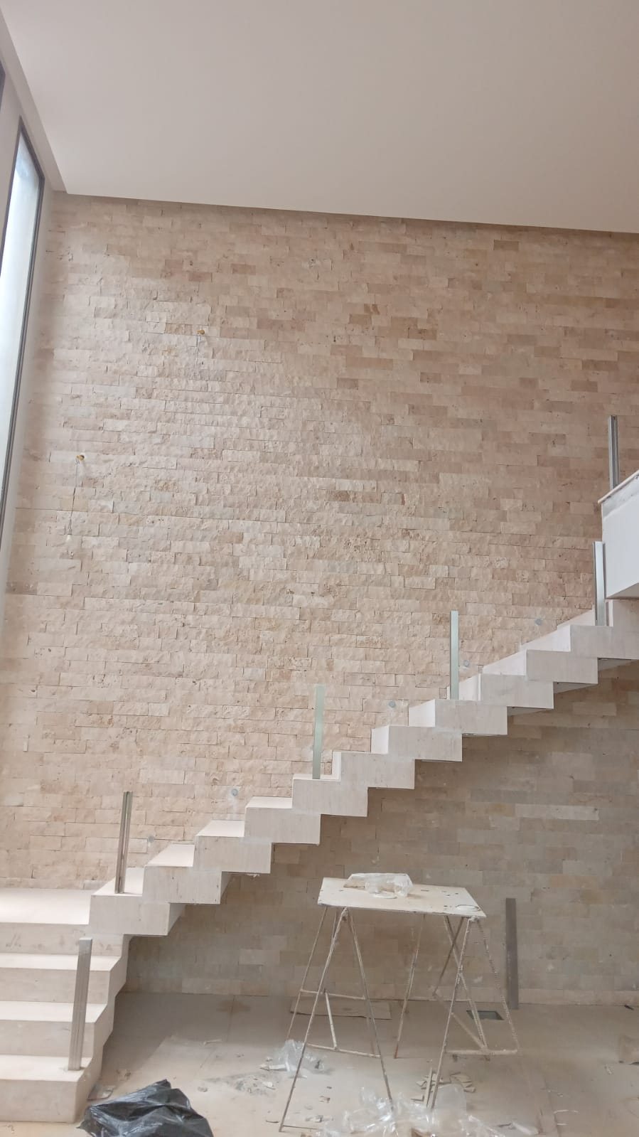 Pano alto de parede em rock face de travertino romano recém assentado, com a obra ainda em execução