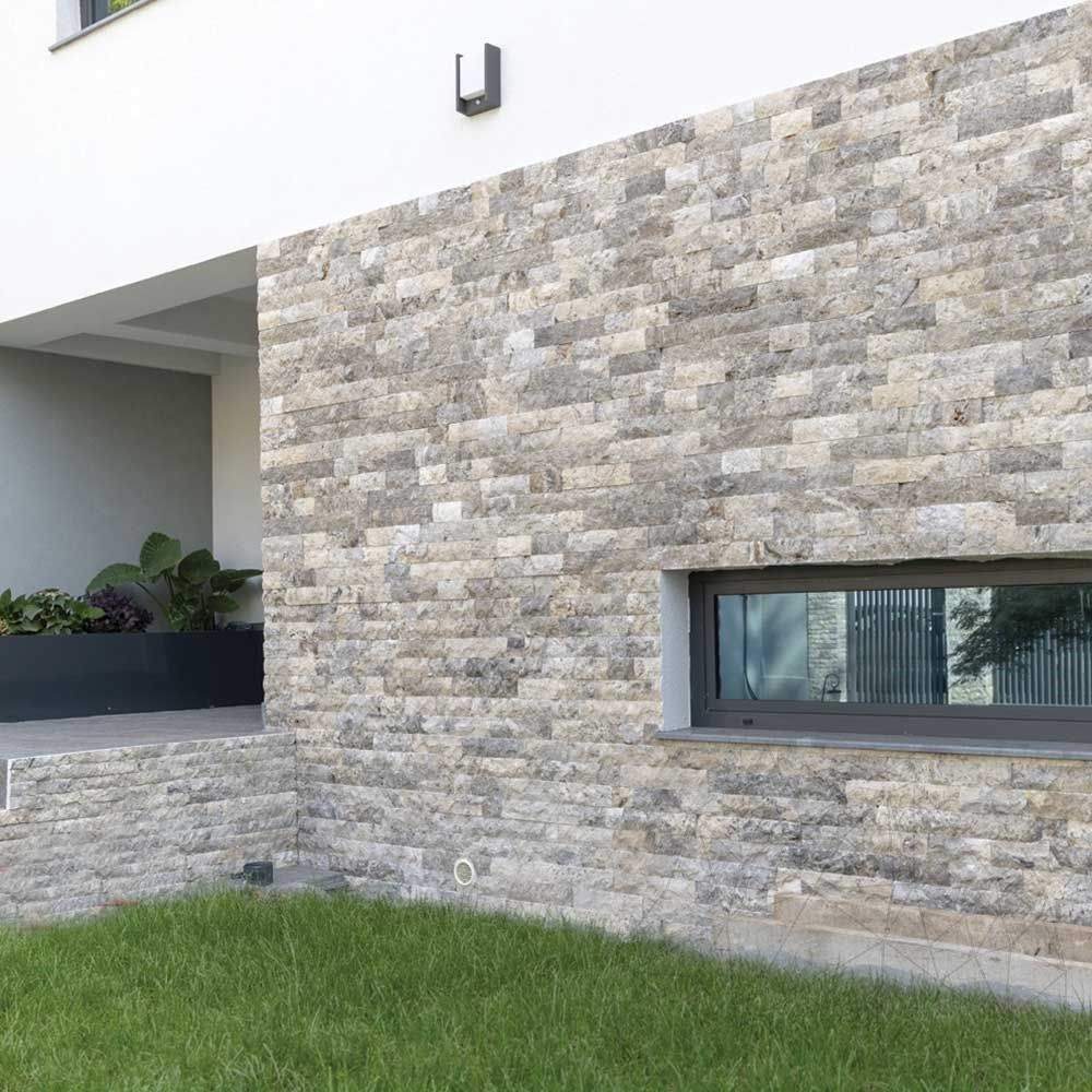 Fachada de casa em rock face de travertino silver cinza, com janela horizontal de esquadria escura e gramado