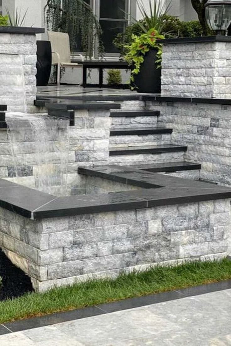 Muro de jardim em Rock Face Travertino Silver acompanhando escada e espelho d'água