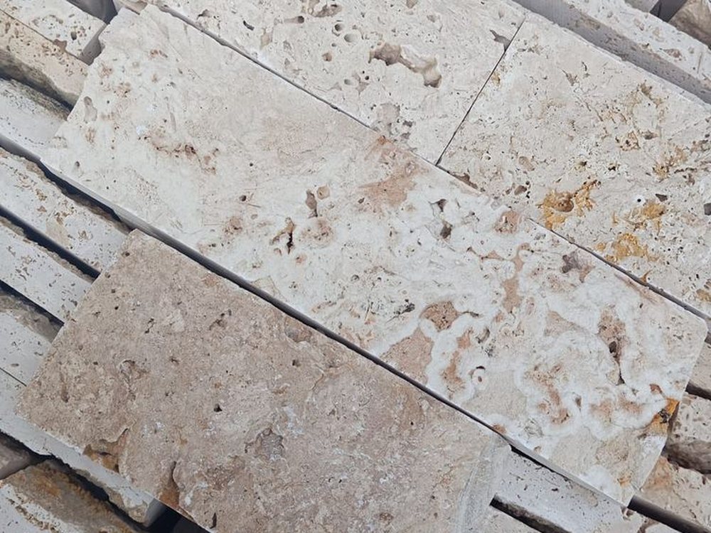 Peças de Rock Face Travertino Romano Mix com variação de tom entre bege, caramelo e marfim